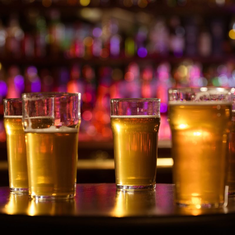 Glasses of cold fresh white light beer on the wooden bar counter in the pub